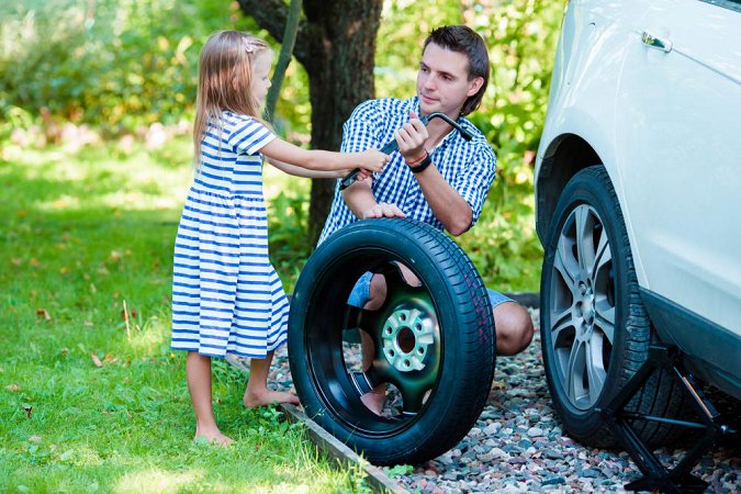 A-little-girl-helping-father-to-change-a-car-wheel-outdoors-on-beautiful-summer-day_png_85