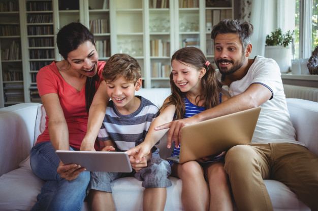 smiling-family-sitting-sofa-pointing-digital-tablet